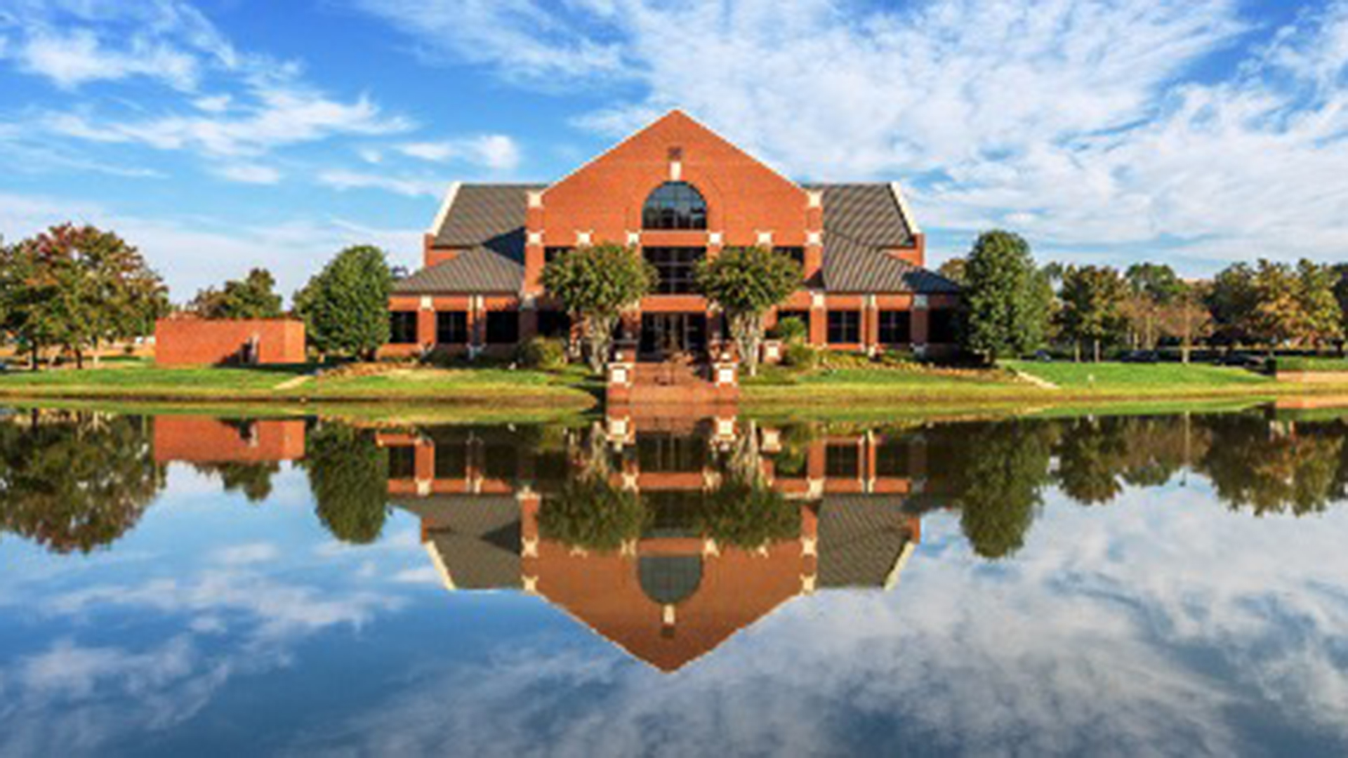 Exterior building photo with building reflection on the water of the neighboring pond