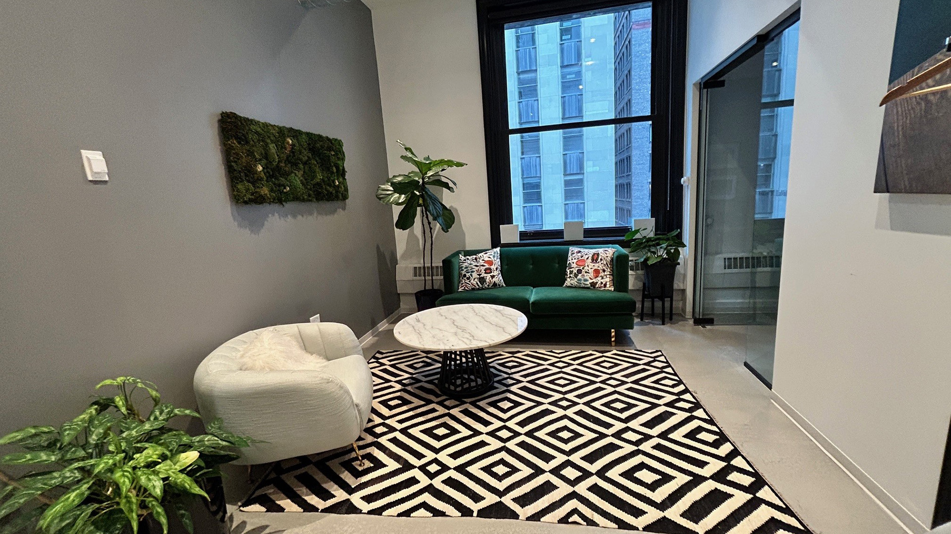 Meeting area with white chair, white table, couch, and black and white carpet inside office at 125 S Clark 