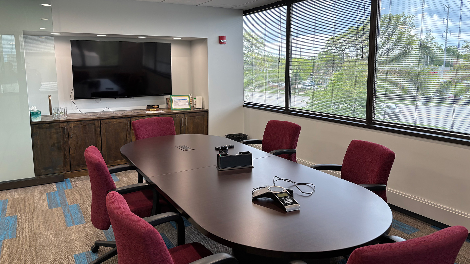 Conference table with maroon chairs and TV in a conference room with windows at 707 Skokie Blvd