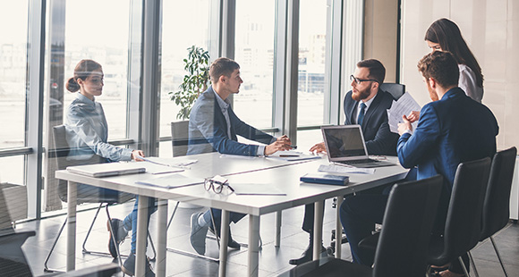 Image: 5 people sitting around glass table