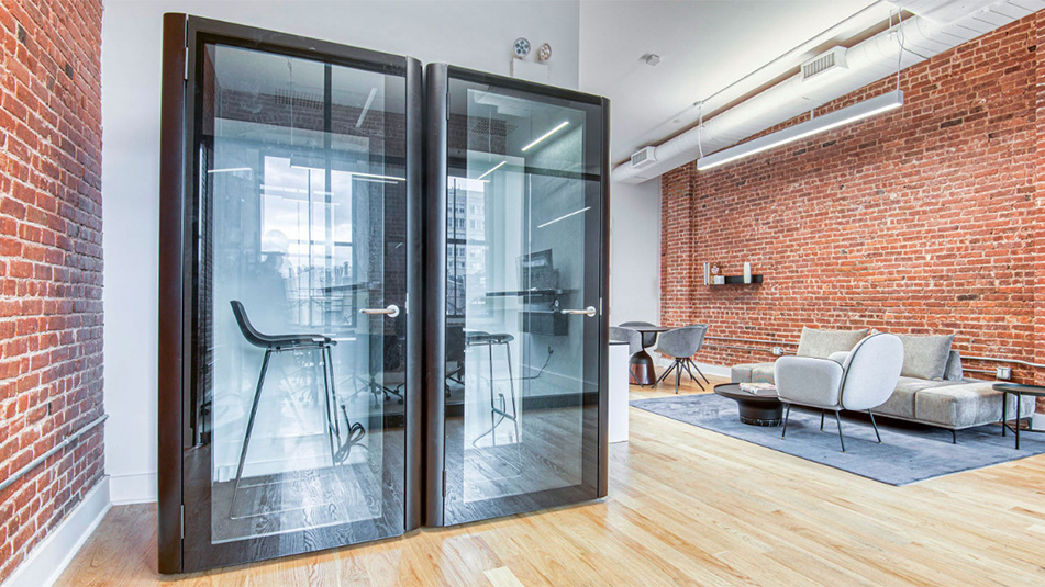 Two glass phone booths with a seating area to the right