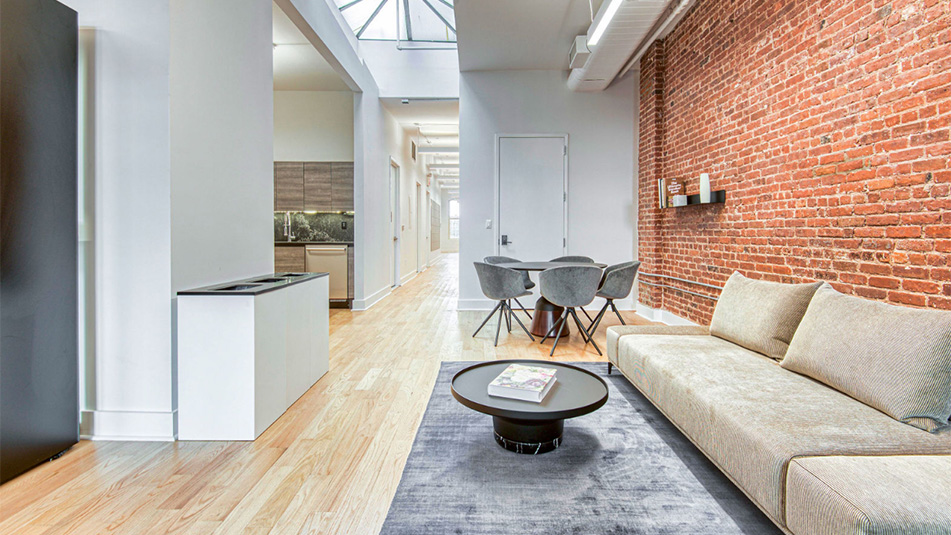 Long sofa seating with brick wall accents and a table and chairs in the background